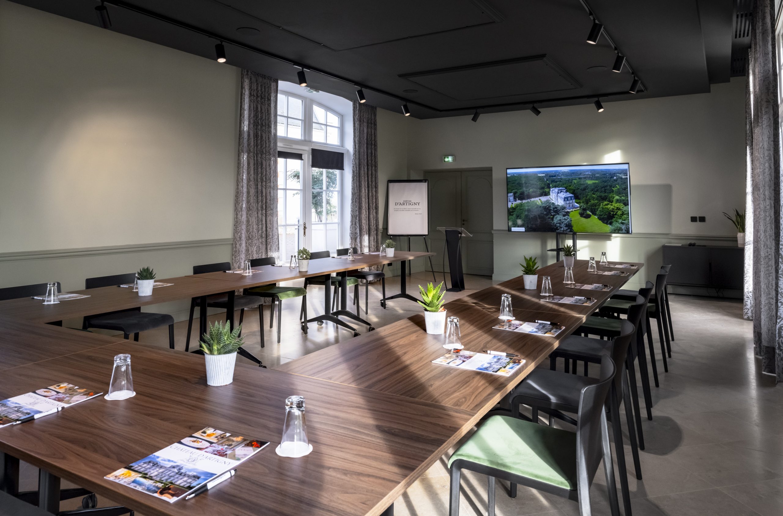 Salle de réunion moderne avec écran et tables en U.